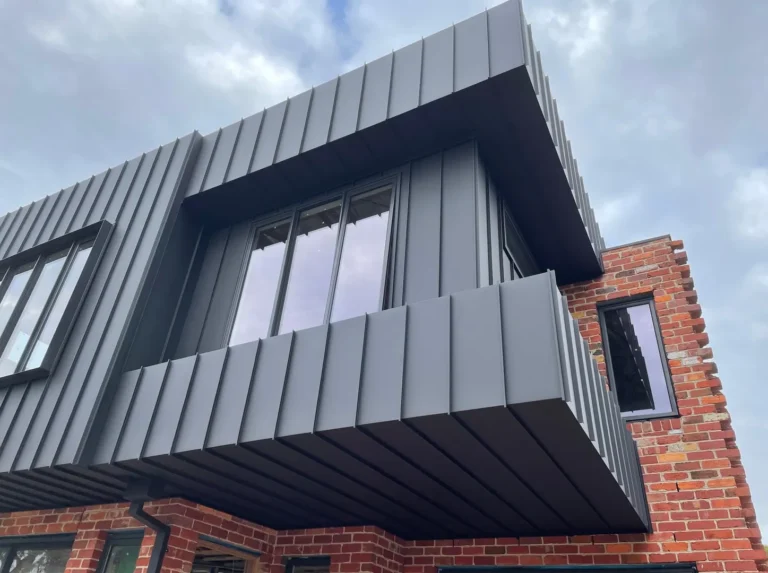 Modern house with metal cladding and brick wall.