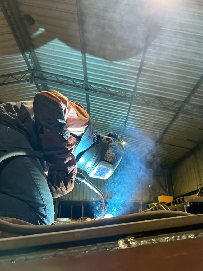Welder working with sparks in industrial setting.