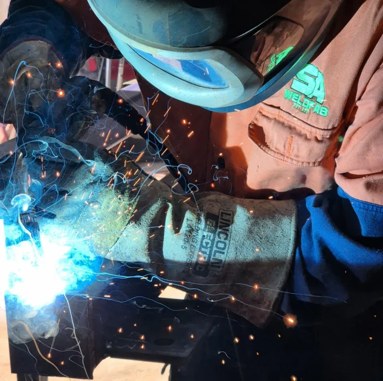 Welder with sparks and safety gear at work.